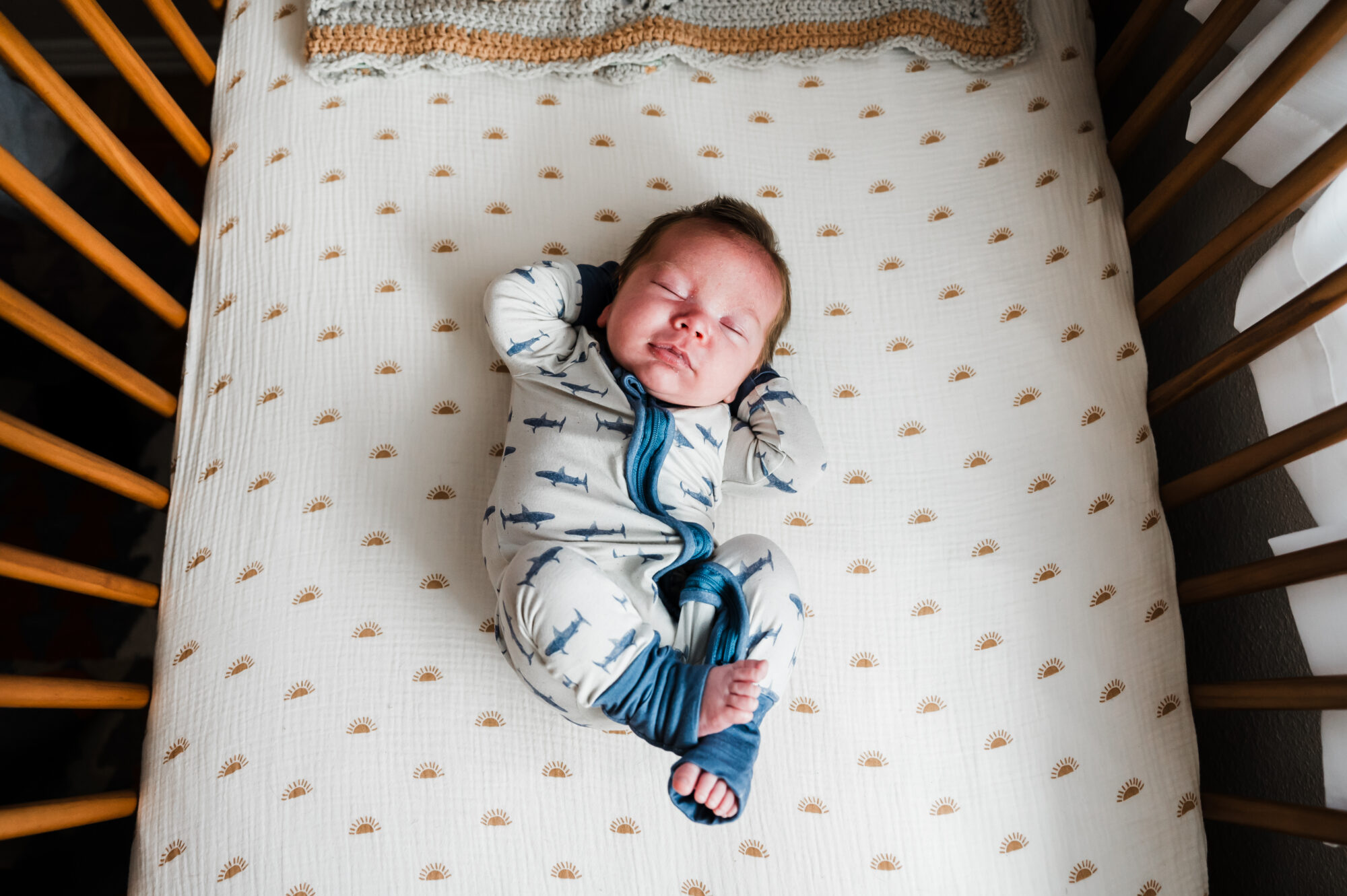 Newborn baby stretching in bed
