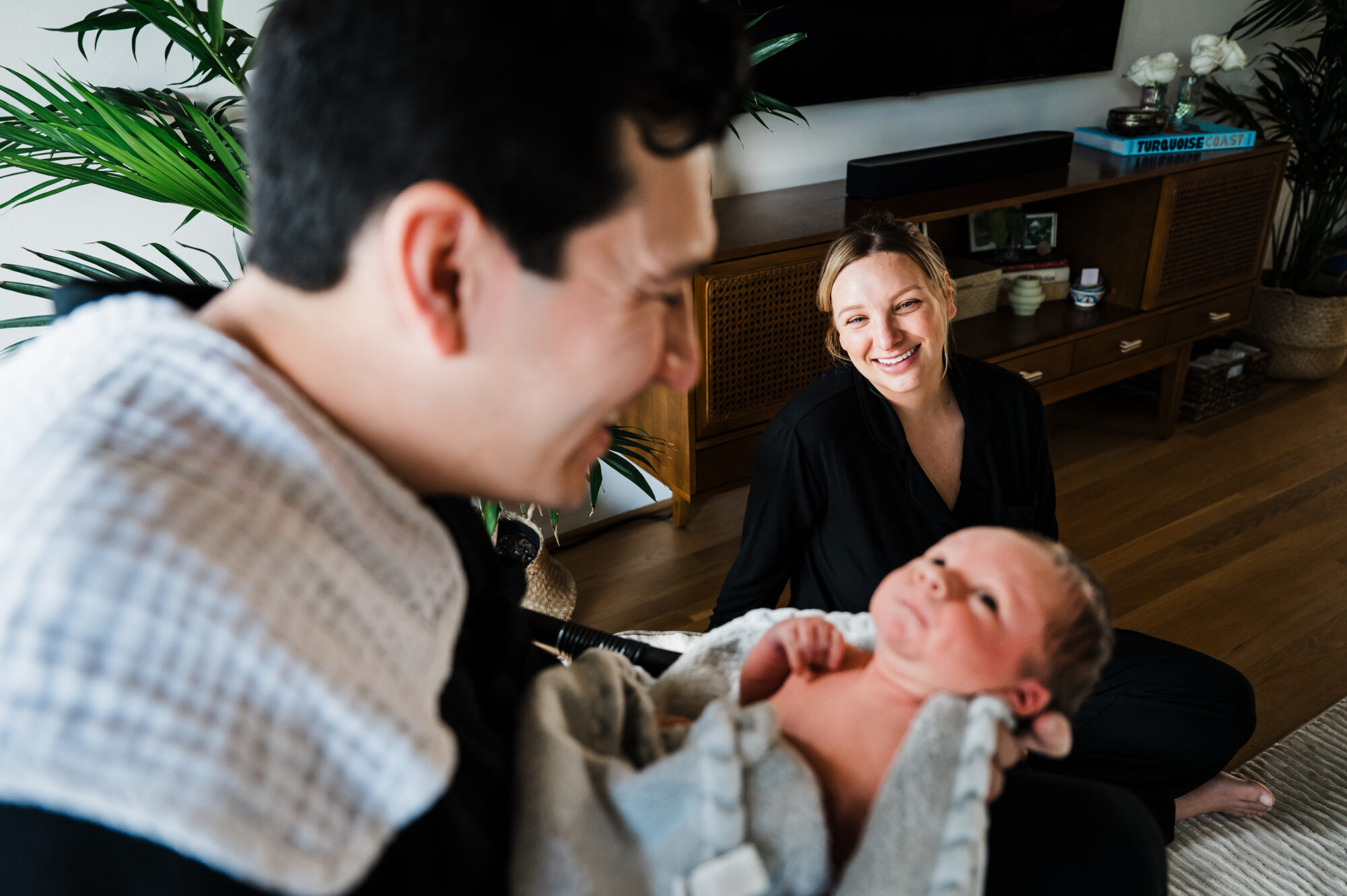 New mom admiring dad holding his newborn during an in-home session