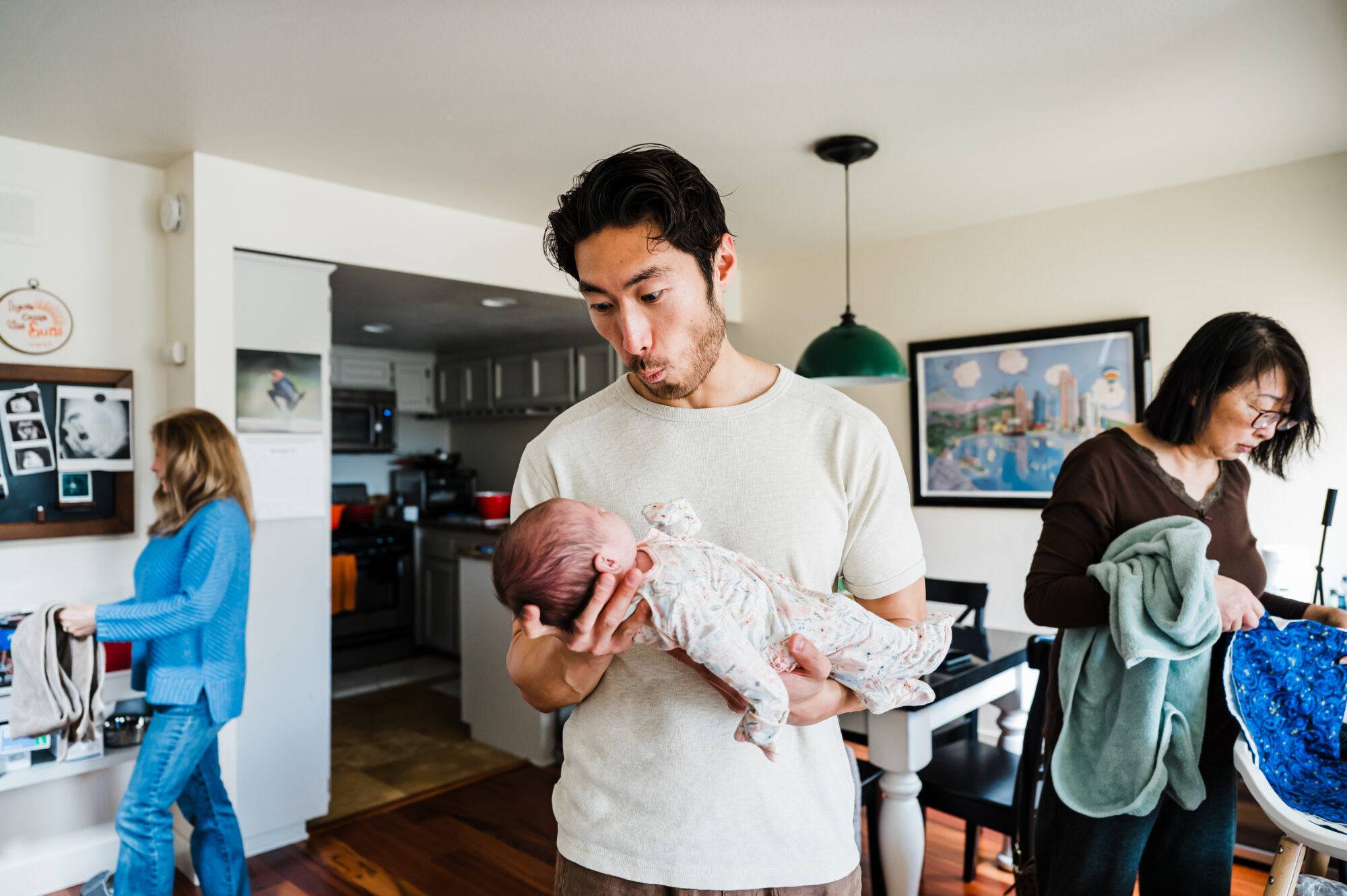 Dad holding his newborn baby with grandmother helping 