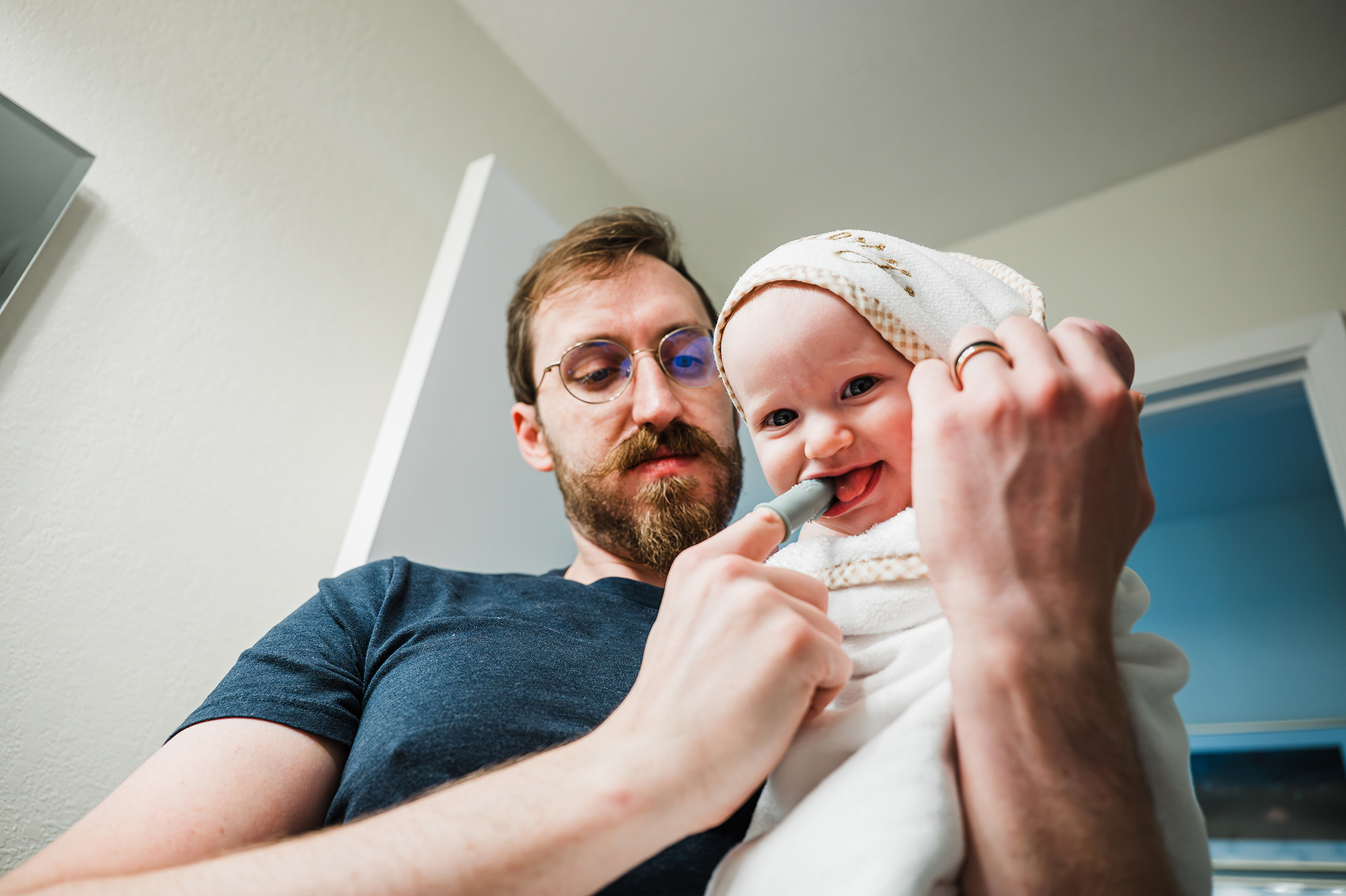 Dad brushing toddler's teeth in their San Diego home